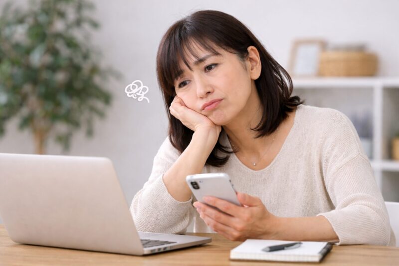 50代女性がブログ作業中に悩み手が止まっている様子｜ブログが続かないイメージ